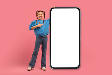 Girl pointing at large smartphone screen on pink background
