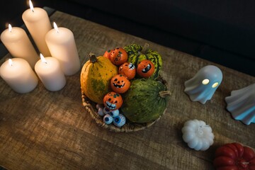 High-angle of Halloween decorations of cups, candles, ghost figures, and pumpkins put on the table