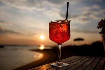 Glass of cocktail in a beach restaurant against sunset background.