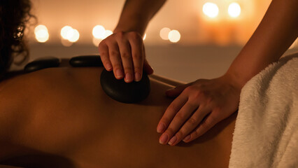 Woman getting hot stones back massage in spa salon - obrazy, fototapety, plakaty