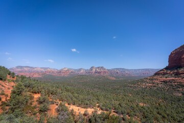 Beautiful view of a green desert and rock formations under a clear blue sky in Sedona, Arizona.
