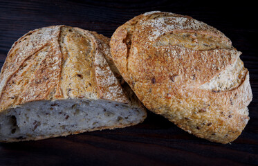 A loaf of bread cut in half on a wooden board. Art bread.