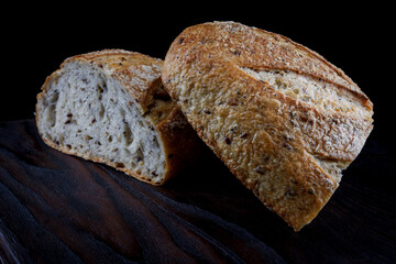 A loaf of bread cut in half on a wooden board. Art bread.