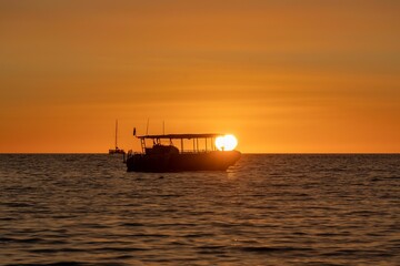Silhouette of a large boat on the water at sunset
