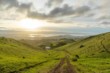 Obraz premium Valley surrounded by green hills at scenic sunset