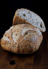A loaf of designer bread cut in half with seeds on a wooden board. Art bread.