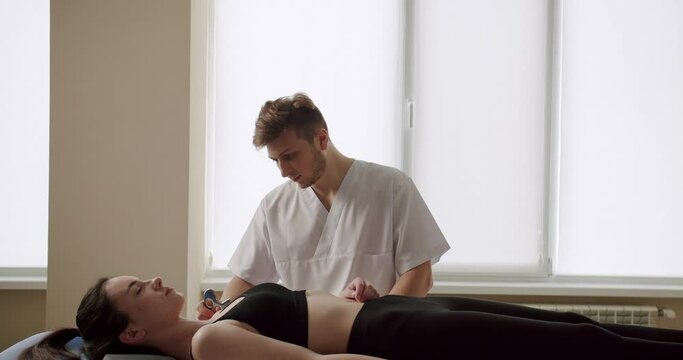 Therapist using IASTM instrument to treat scapular pain, performing fascia release manipulations soft tissue treatment on her neck. IASTM, myofascial Release For Rhomboid And Pain Using Smart Tools