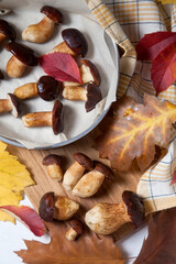 Several Imleria Badia or Boletus badius mushrooms commonly known as the bay bolete, vintage baking sheet with mushrooms on wooden cutting board..