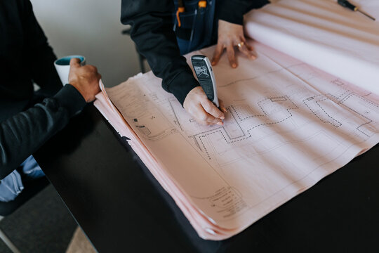 High angle view of mid section of people using blueprints in office