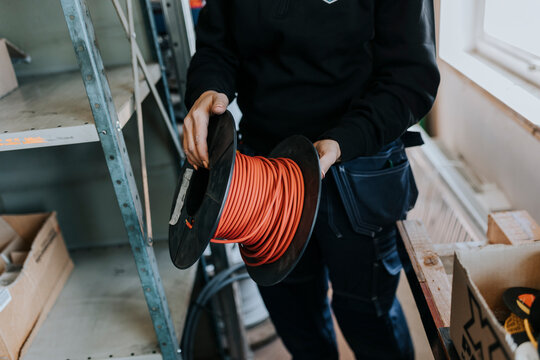 Mid section of man holding reel with cables