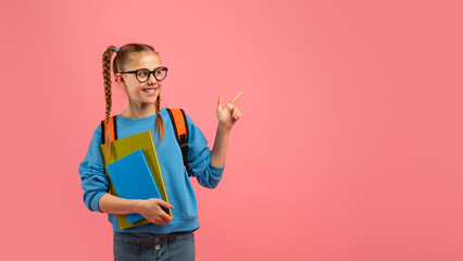 Girl with glasses pointing up on pink backdrop