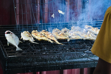A man is grilling fresh fish