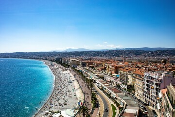 Drone shot of people on the sandy beach and the coastal buildings on a sunny day in Nice, France