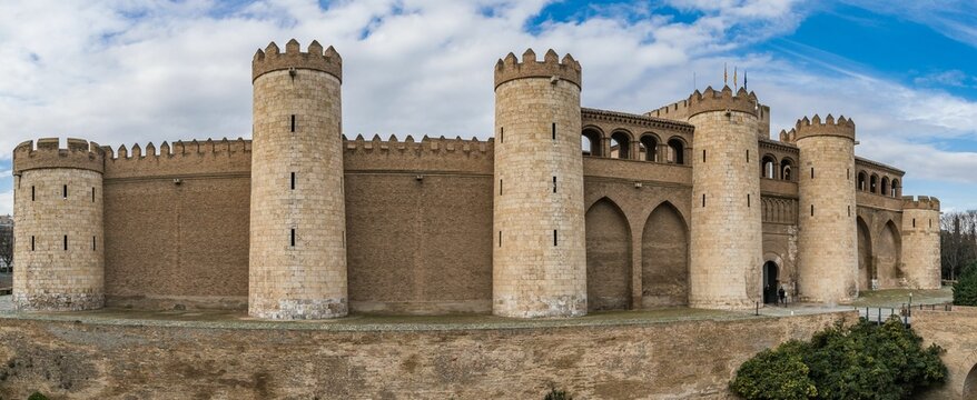 Image of an Aljaferia Palace on the top of the mount under the cloudy blue sky.