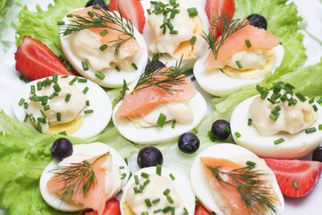 Boiled eggs with mayo. Smoked salmon. Party snack background. Easter food. Healthy breakfast in tapas style. Chives and dill food decoration.