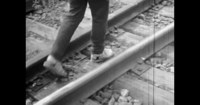 Man legs walk along railway tracks, close up. Vintage black white film. Retro archive 1980s. Walking along train tracks in countryside. Adventure travel by railroad transportation. Old wood rail road