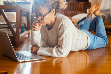 One concentrate woman at home using laptop laying on the floor alone. Bank account management,...