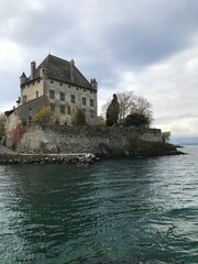 Fototapeta na wymiar Vertical shot of Yvoire Castle against a lake on a cloudy day in France