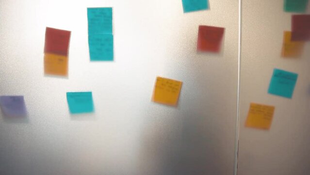 Colorful sticky notes on transparent glass.