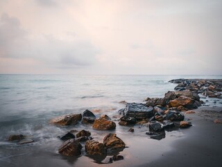 Sea waves calmly hitting a sandy beach with stones