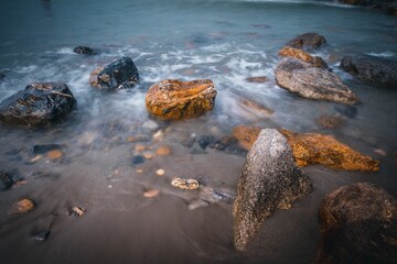 Golden sunrise over the sea waves with stones on the water