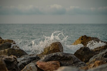 Golden sunrise over the sea waves with stones on the water
