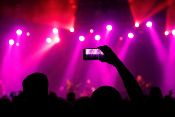 Capturing the electrifying atmosphere of a live music event, an audience member recording or taking a photo with their smartphone