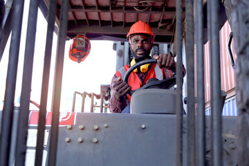 Industrial worker man wearing safety bright neon red vest and helmet driving forklift car at plant...