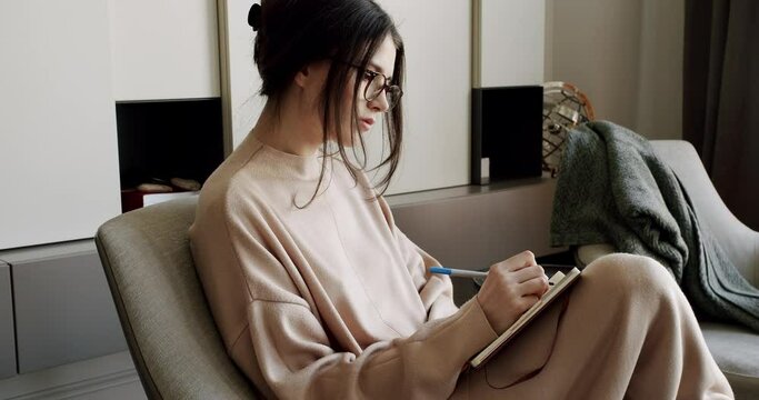 Attractive Woman freelance writer is writing his article on a notebook. idea and inspiration concept. Businesswoman writes startup business ideas and plans, creative thoughts to notebook.