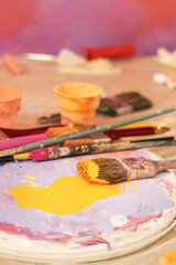 Palette with yellow paint and brushes, home renovation, preparation for wall painting