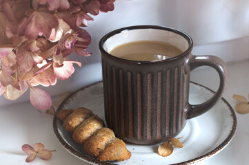 Morning mug of cappuccino with a cookie. Window, natural light, flowers and coffee. Selective Focus