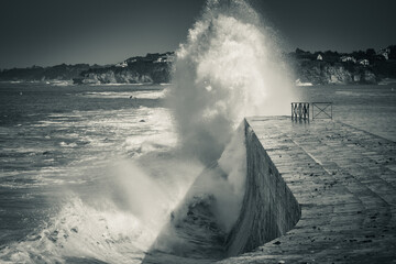 huge wave splash against the dike, in black and white