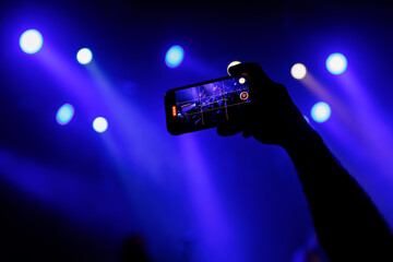 Fototapeta na wymiar Making photo with smartphone during a concert to share the moment with friends on social networks.