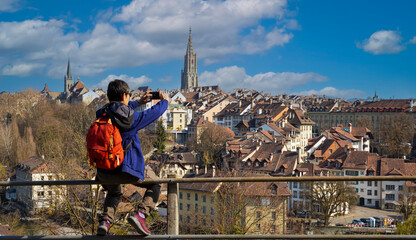 Back view young tourist man in packpack using smartphone take picture at old Town of Bern, capital of Switzerland