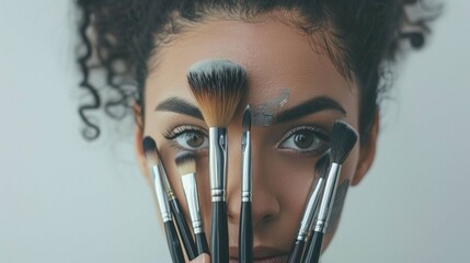 Portrait of a make-up artist hiding her face with brushes on the white background