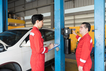 Two male mechanic working at garage. Asian men mechanics checks, repair and maintenance at auto car...