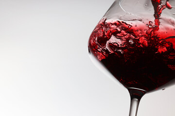 Pouring tasty red wine in glass on white background, closeup. Space for text
