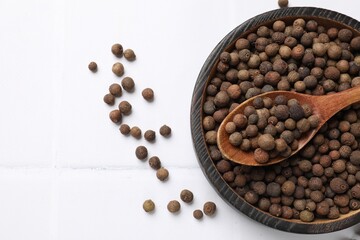 Dry allspice berries (Jamaica pepper) on white tiled table, top view. Space for text