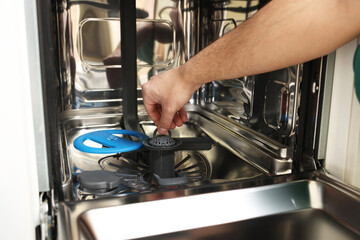 Repairman pulling drain filter out of dishwasher, closeup