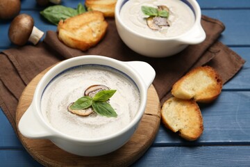 Fresh homemade mushroom soup ceramic pots on blue wooden table
