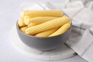 Tasty fresh yellow baby corns in bowl on white table