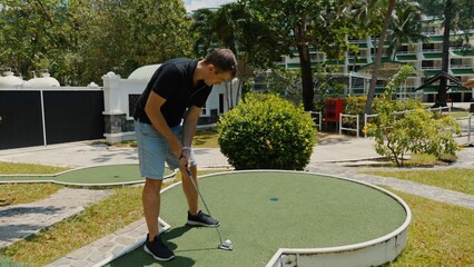 Man playing mini-golf outdoors on sunny day with focus on leisure activities and outdoor sports. Enjoyment and recreational pursuit.