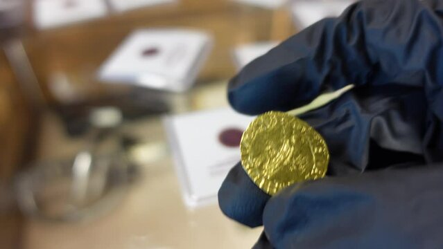 Collector examining Portuguese gold coin from the Age of Discoveries
