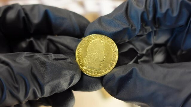 Collector examining Portuguese ancient golden coin