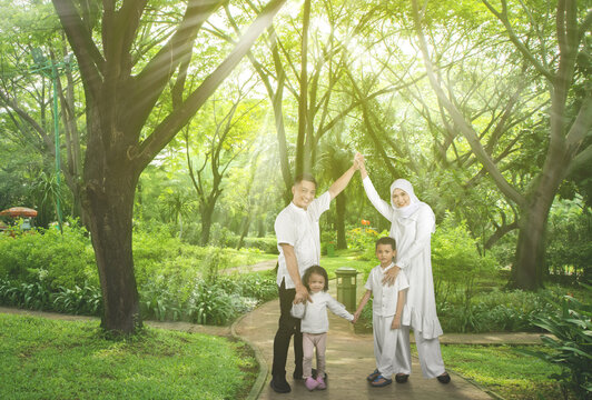 Happy Asian muslim family of four having fun together at park