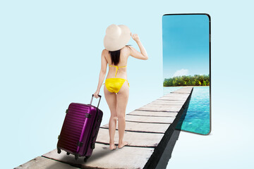 Rear view of a woman in bikini pulling a suitcase on wooden jetty