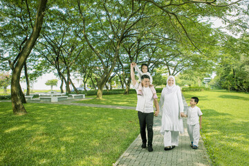 Front view of joyful happy Asian muslim family walking together