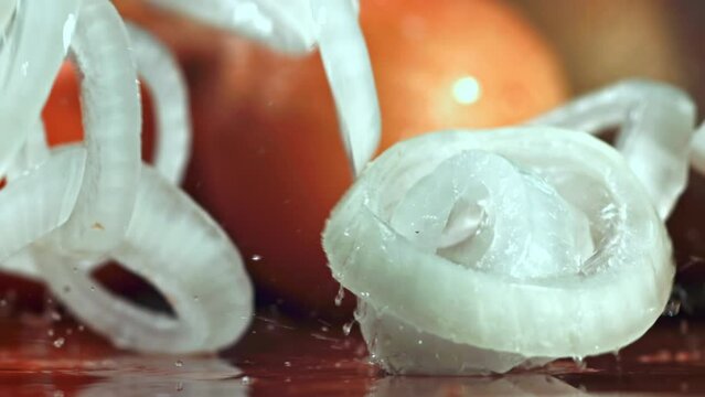 Super slow motion Sliced onion falls on the wet table. High quality FullHD footage