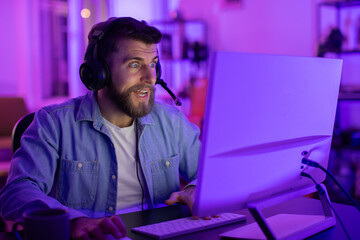 Focused gamer at a computer in blue light