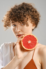 Woman holds half of grapefruit in hand